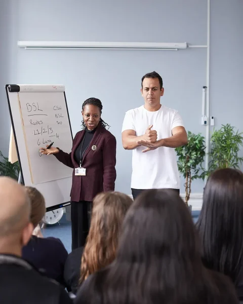 Sign language teachers in front of a flipchart.